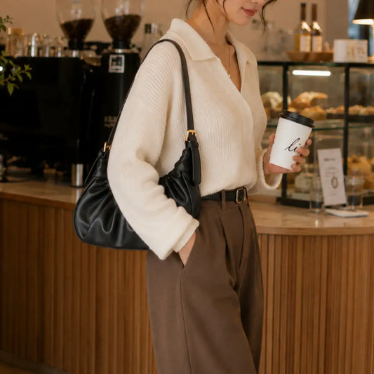 Modelo numa cafetaria com a mala de ombro Chloe preta ao ombro