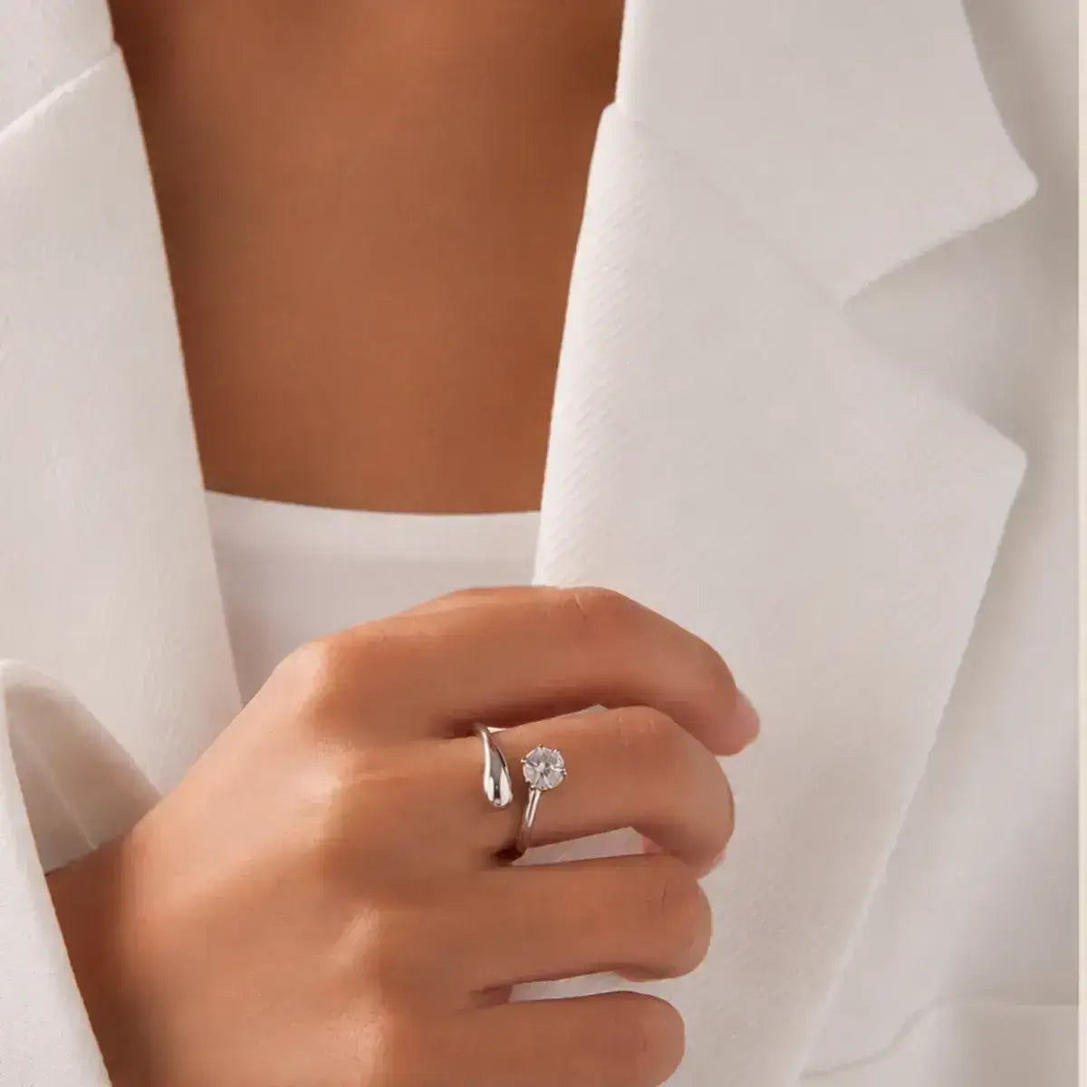 Anel aberto em prata 925 com moissanite na mão da modelo com blaser branco