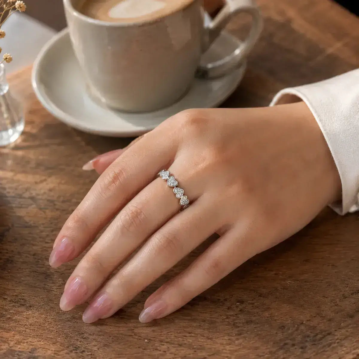 Anel corações em prata 925 cravejados com moissanite em close na mão da modelo