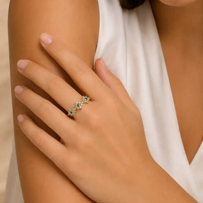 Anel em prata 925 dourada com três flores em moissanite ciano e preto no centro na mão da modelo