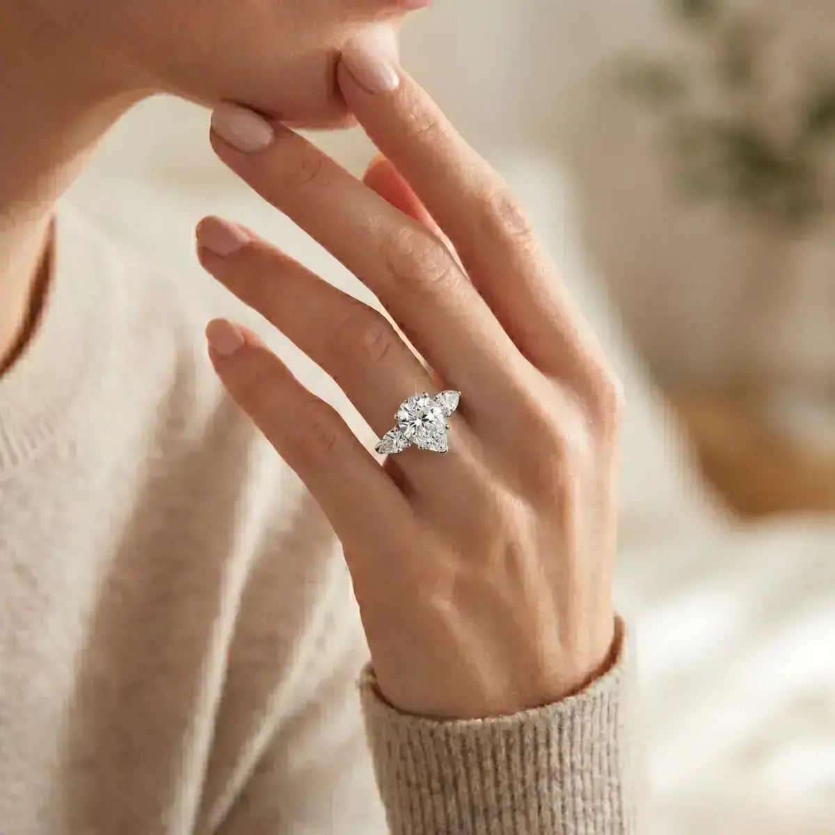Imagem de mão feminina delicada, usando anel solitário gota de prata com com moissanite em ambiente iluminado