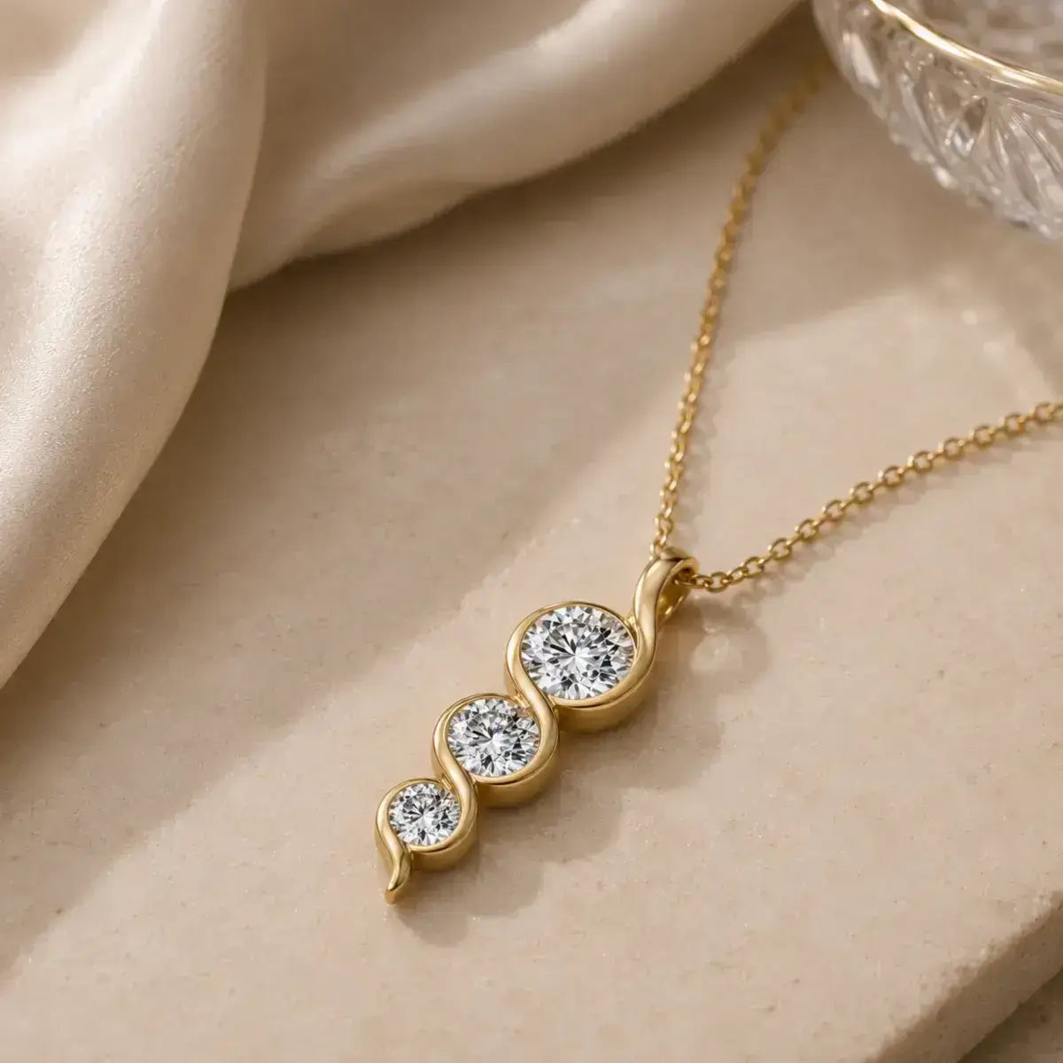 Colar dourado em Prata 925 com pendente em espiral e três moissanites sobre fundo elegante