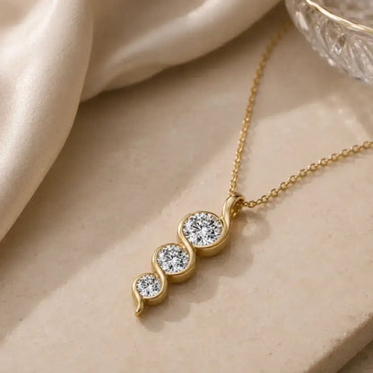 Colar dourado em Prata 925 com pendente em espiral e três moissanites sobre fundo elegante