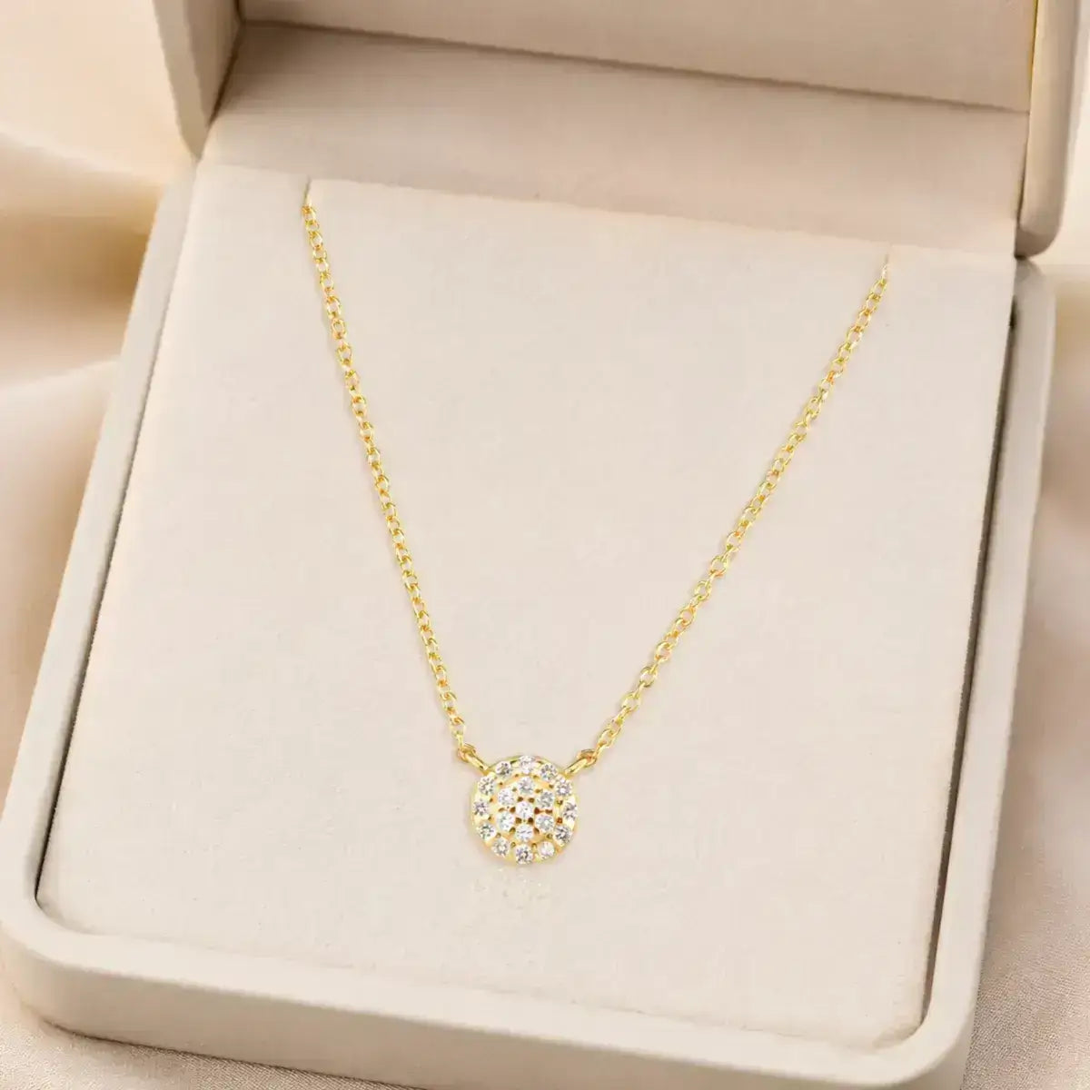 Colar em prata 925 dourada com pendente circular com zircónias em uma caixa de joias branca