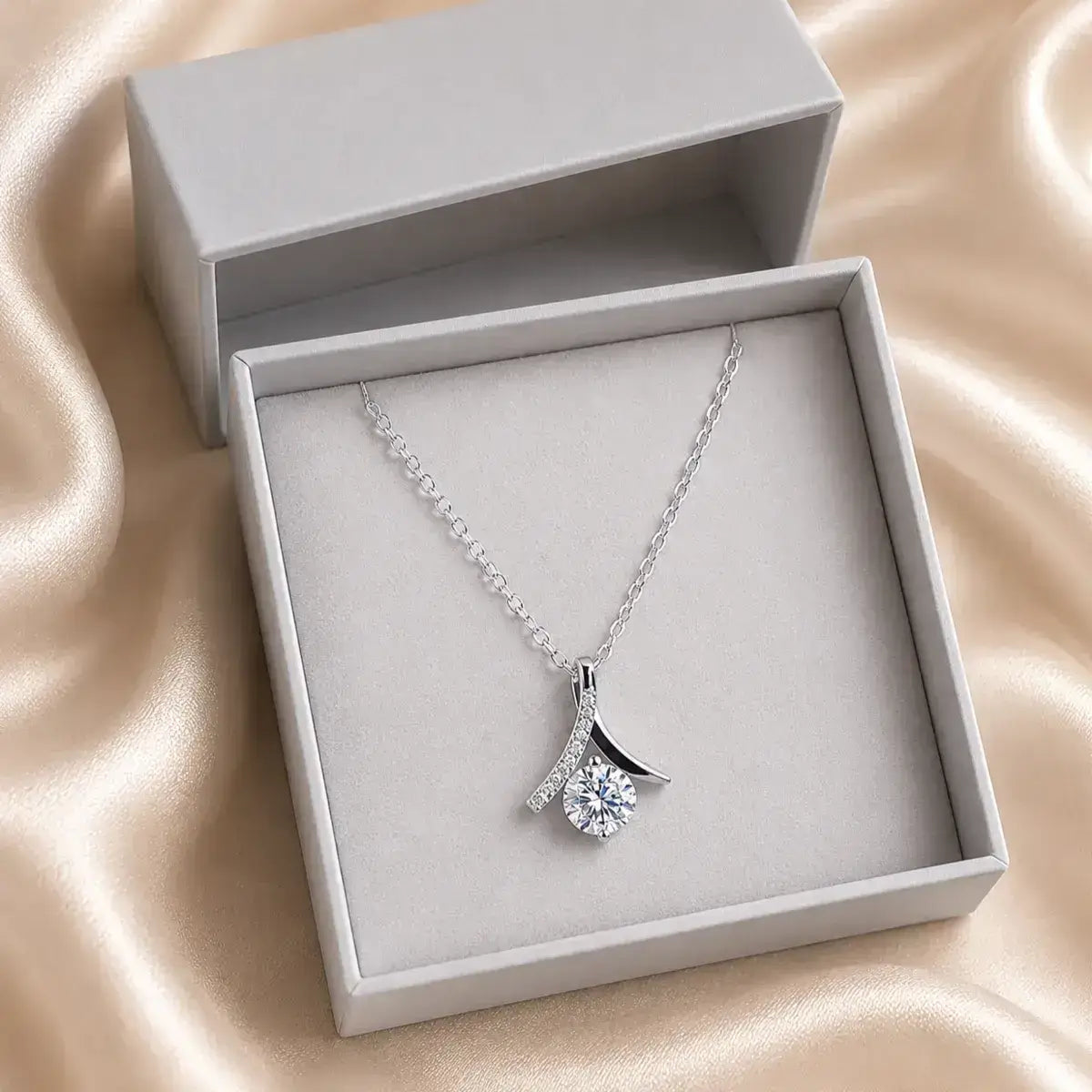 Colar solitário em prata 925 com moissanite e pendente inspirado no símbolo do infinito em caixa de joias cinzenta sobre tecido acetinado