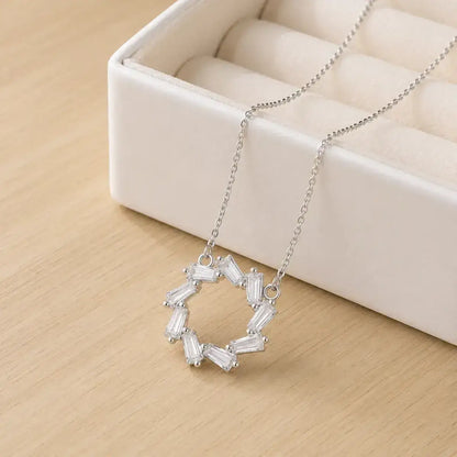 Colar em Prata de Lei 925 com pendente circular de zircónias baguete junto a caixa de joias elegante.