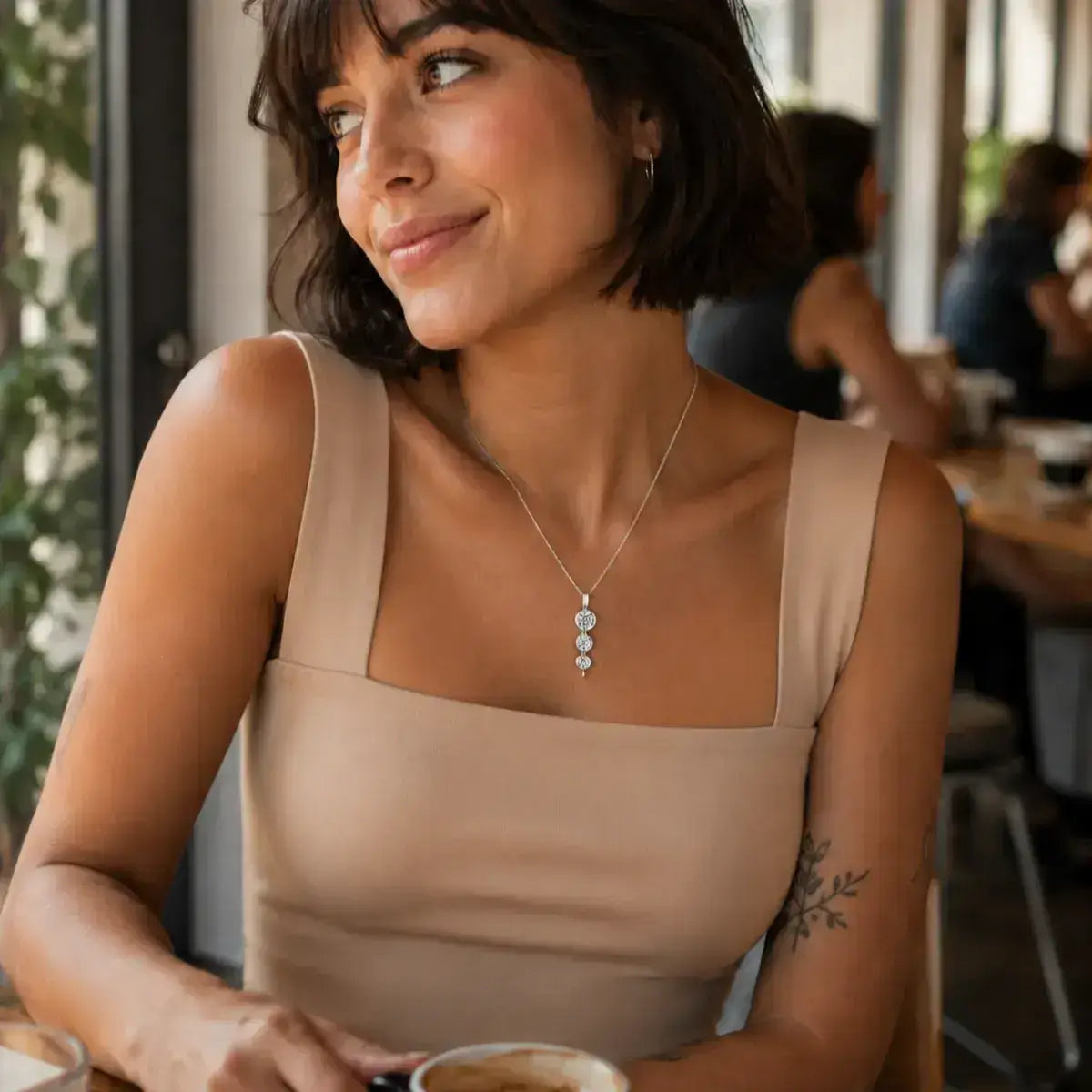 Mulher em ambiente de cafeteria a usar colar em Prata 925 com pendente em espiral e três moissanites