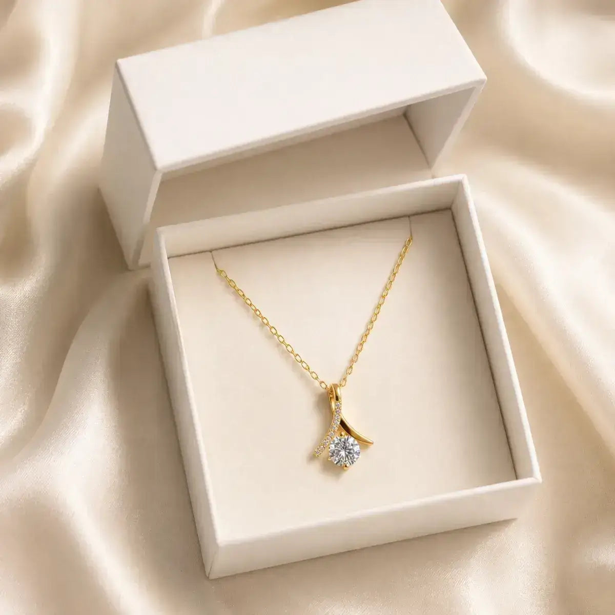 Colar solitário em prata 925 dourada  com moissanite e pendente inspirado no símbolo do infinito em caixa de joias branca sobre tecido acetinado