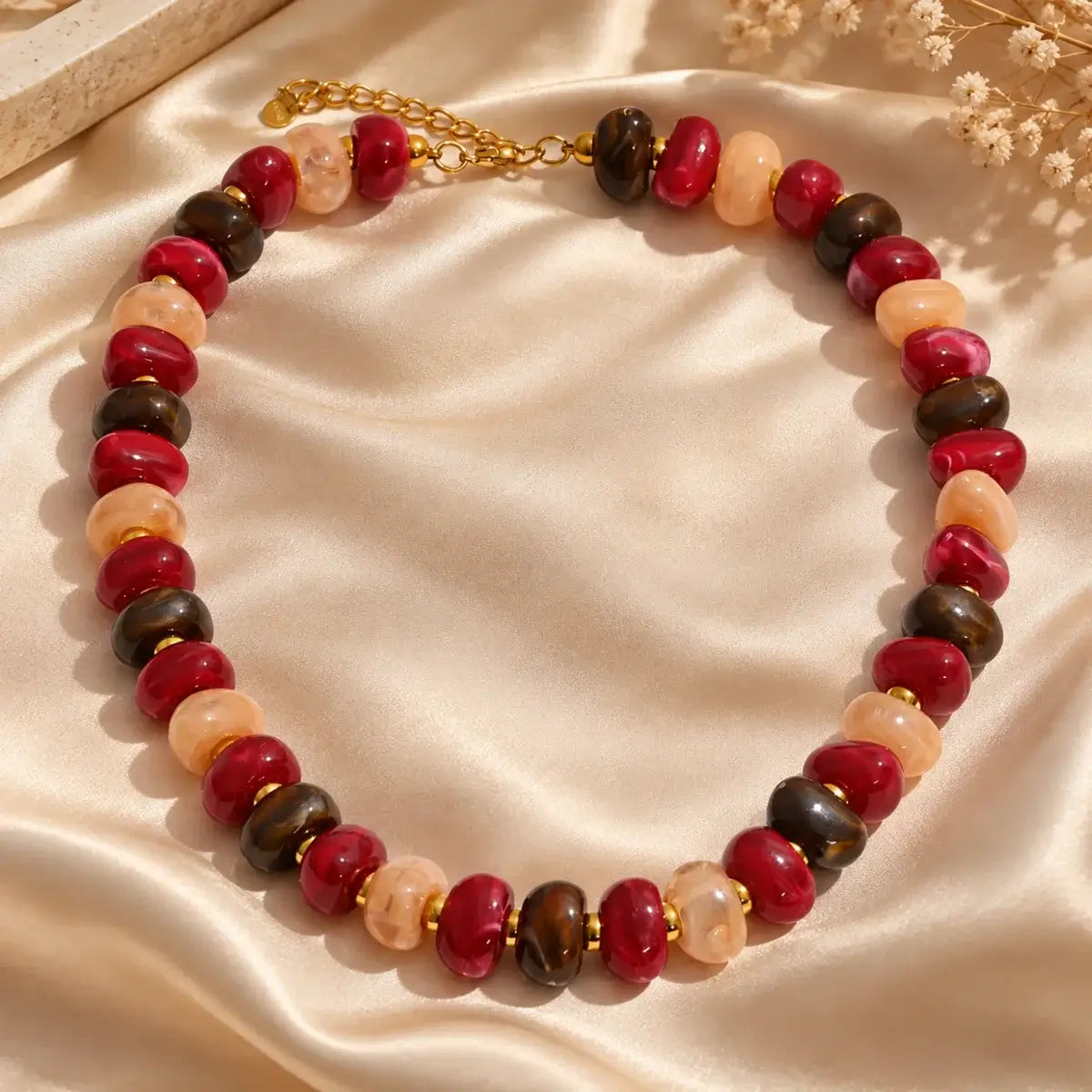 Colar de resina com contas multicoloridas vermelho, bege, castanho, sobre tecido de seda champagne