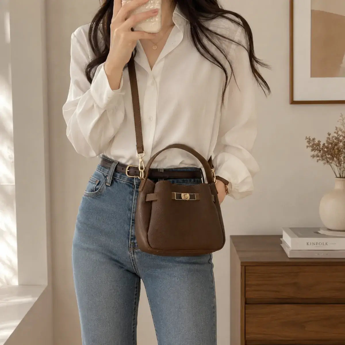 Modelo a usar a Mala Tiracolo Élia em pele sintética premium castanha com calças de ganga e camisa branca