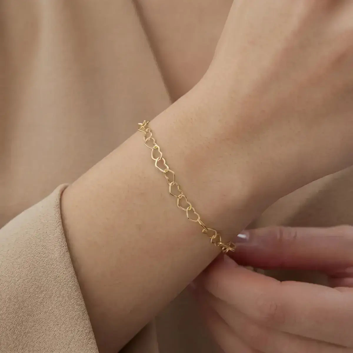 Pulseira elo coração em prata certificada dourada em close no pulso da modelo