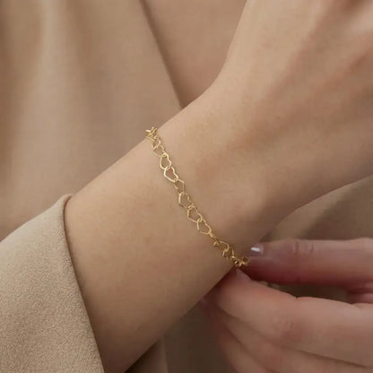 Pulseira elo coração em prata certificada dourada em close no pulso da modelo