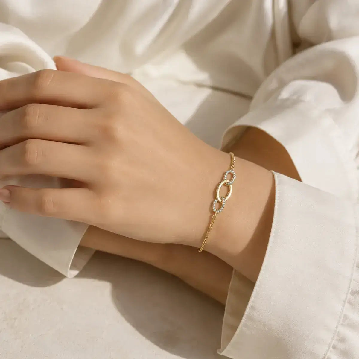 Pulseira com elos entrelaçados de moissanite em prata 925 dourada no pulso da modelo