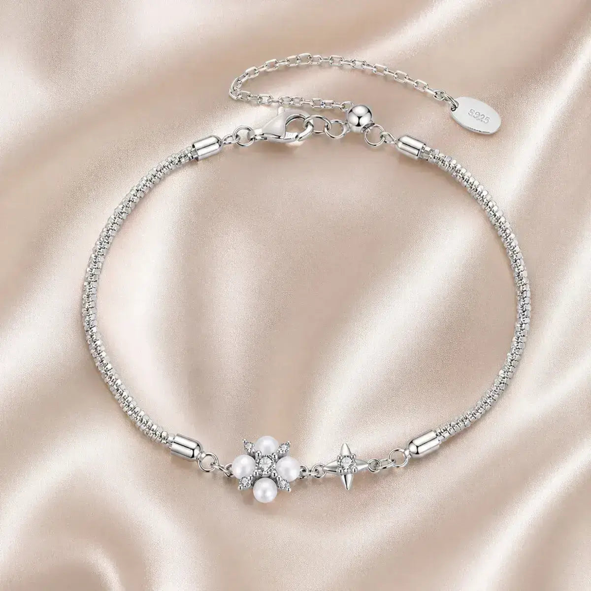Pulseira em Prata de Lei 925 com pérola natural e moissanites em detalhe de estrela sobre tecido cetim bege