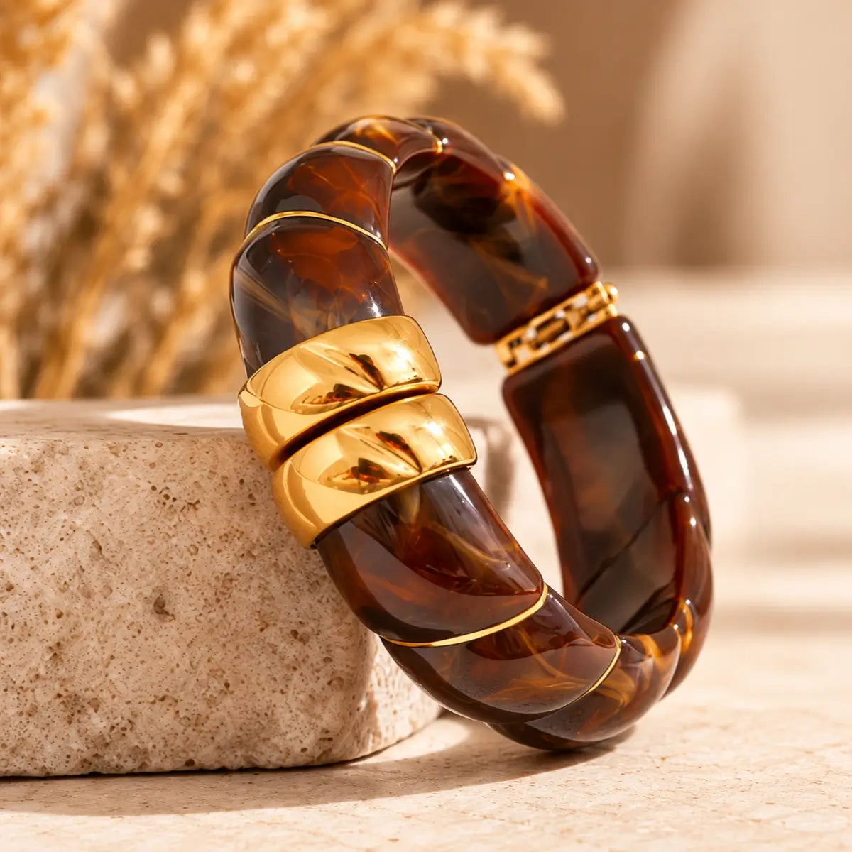 Pulseira de resina castanha larga com design geométrico e acabamento dourado de lado